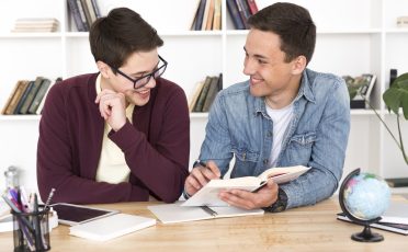 smiling-students-reading-book-min